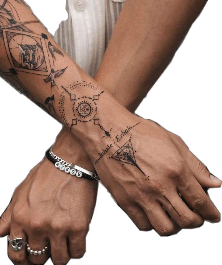 Geometric forearm tattoos with Inhale/Exhale design and bracelet reading HYGGE on crossed arms.