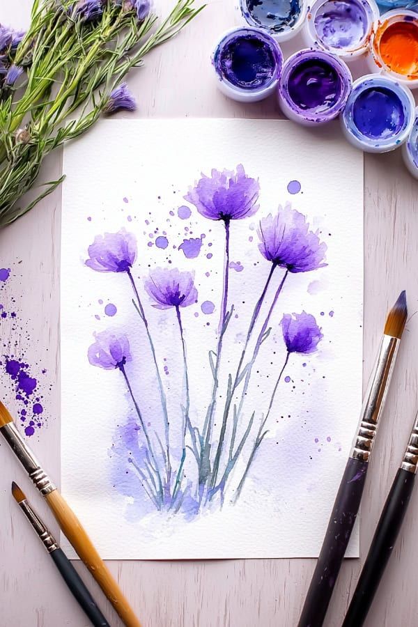 Watercolor painting of purple flowers with paintbrushes and paint jars on a wooden table.