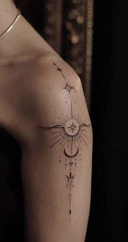 Elegant celestial tattoo featuring stars and abstract sun design on upper arm.