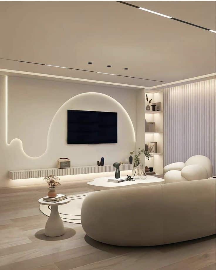 Modern minimalist living room with neutral tones, curved sofa, wall-mounted TV, and elegant lighting.
