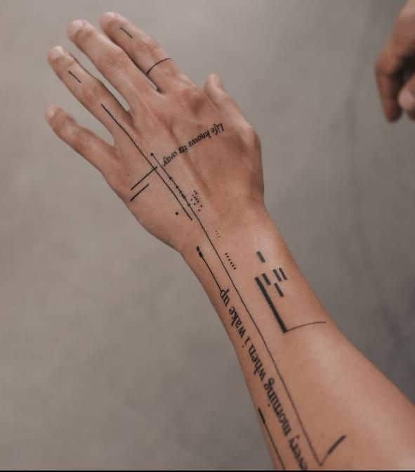 Abstract line and text tattoo on a hand with geometric and minimalist design elements.