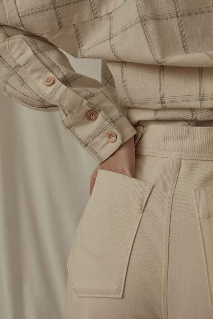 Beige plaid shirt and pants, hand in pocket, showcasing minimalist fashion and neutral tones.