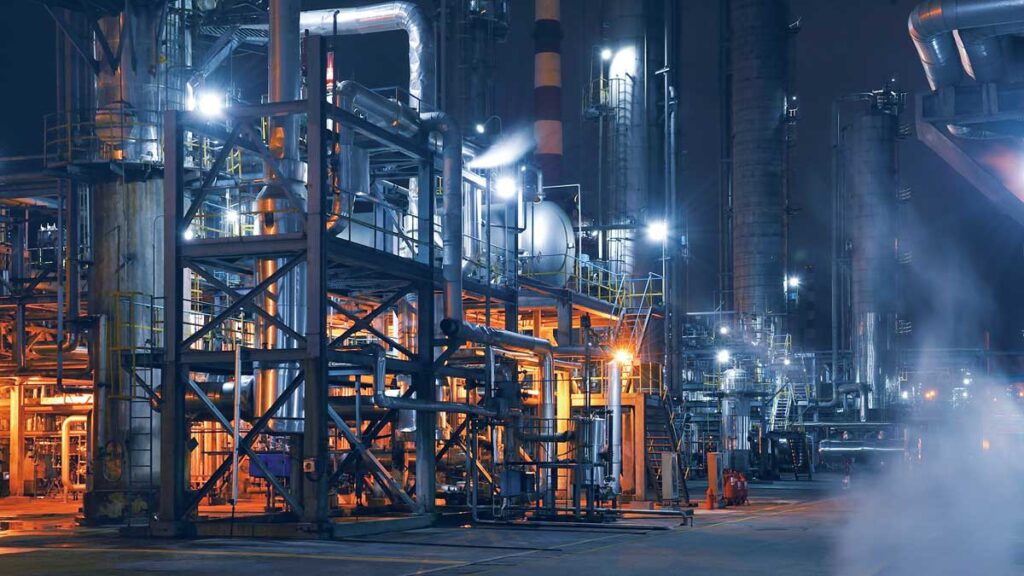 Industrial plant at night with illuminated machinery and infrastructure.