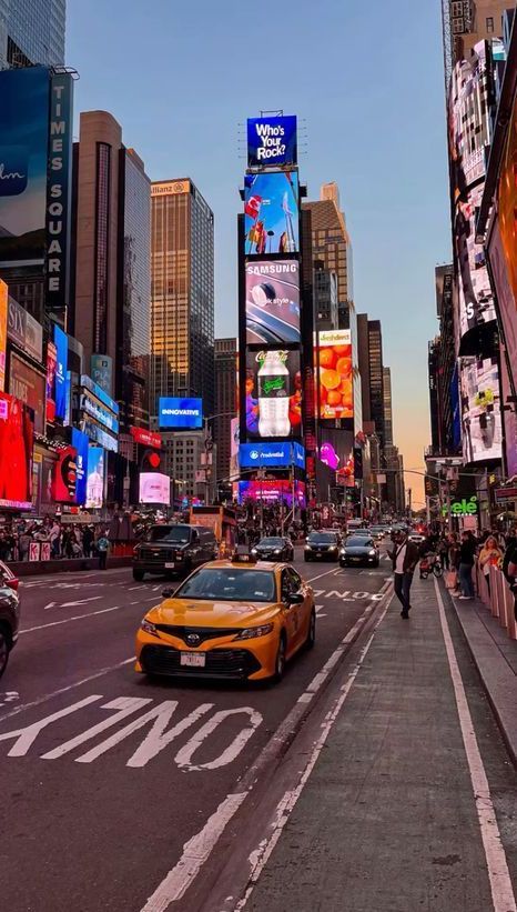 Times Square bustling with cars and neon billboards at sunset, showcasing vibrant city life and advertising displays.