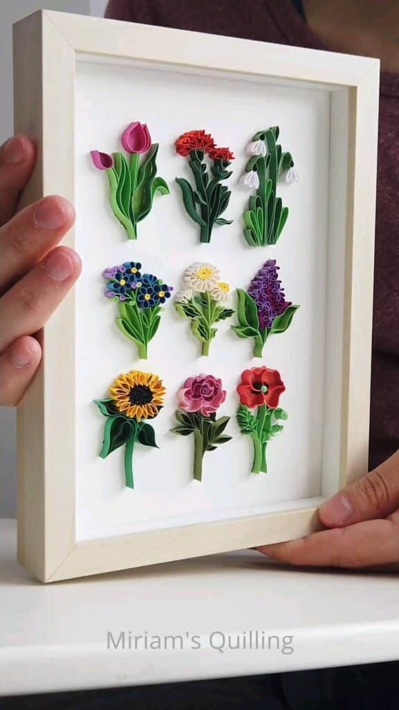 Framed quilled flowers artwork showcasing colorful floral designs in a wooden frame.