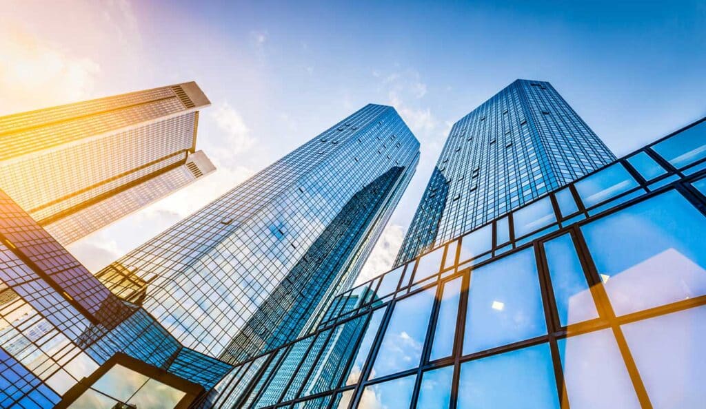 Modern skyscrapers with glass facades reflect sunlight against a blue sky, showcasing urban architecture.