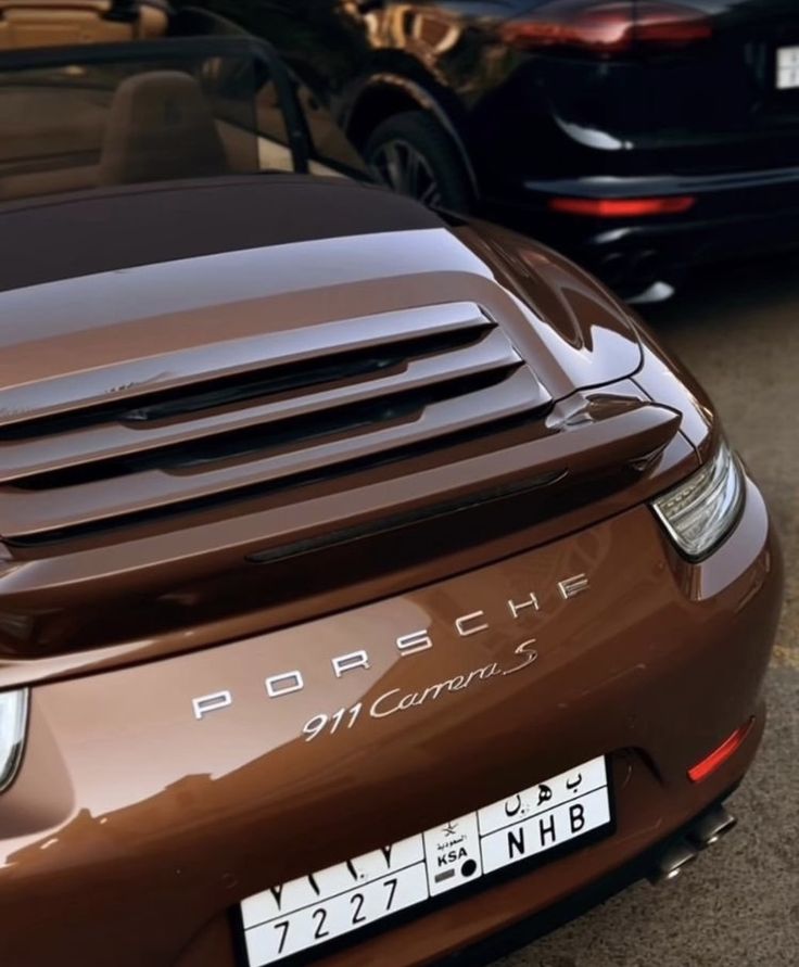 Brown Porsche 911 Carrera S sports car, rear view, parked on a street in daylight.