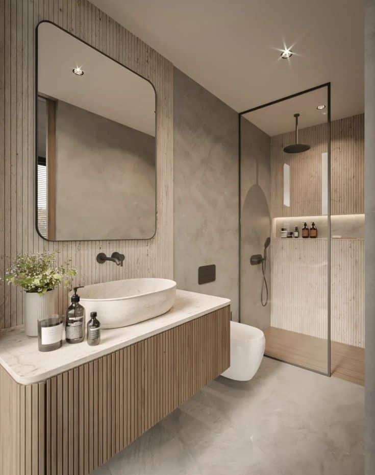 Modern bathroom with minimalist design, featuring a wood vanity, large mirror, and glass shower enclosure.