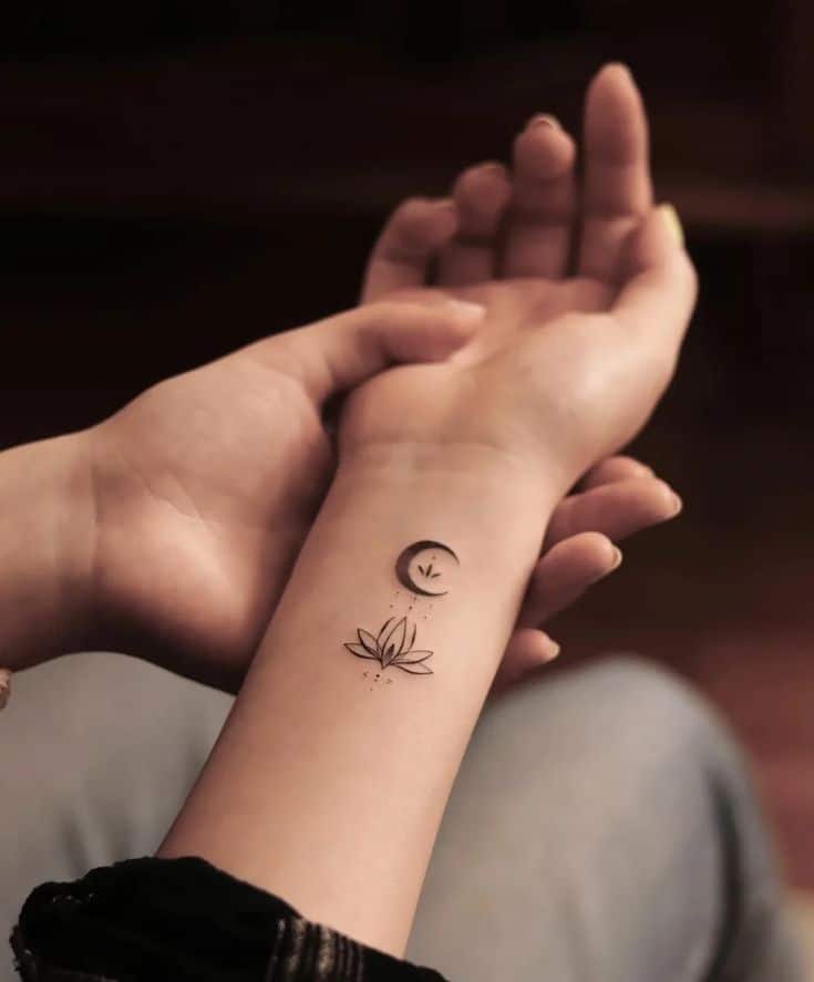 Minimalist tattoo of a crescent moon and lotus on a person's wrist, symbolizing serenity and balance.