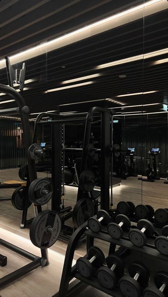 Modern gym with mirrored walls, featuring various weights and exercise equipment. Perfect for strength training.