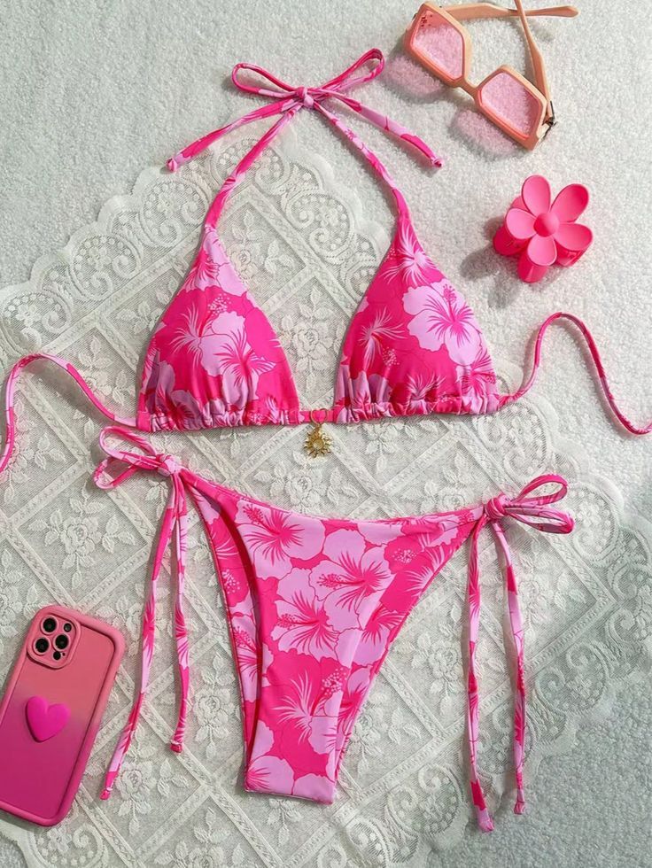 Bright pink floral bikini set with sunglasses, phone, and flower accessory on lace background. Summer beach essentials.