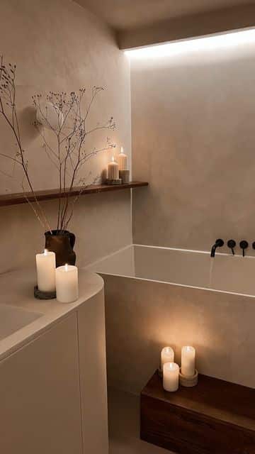 Minimalist bathroom with a luxurious bathtub, ambient candlelight, and elegant decor for a relaxing spa-like atmosphere.