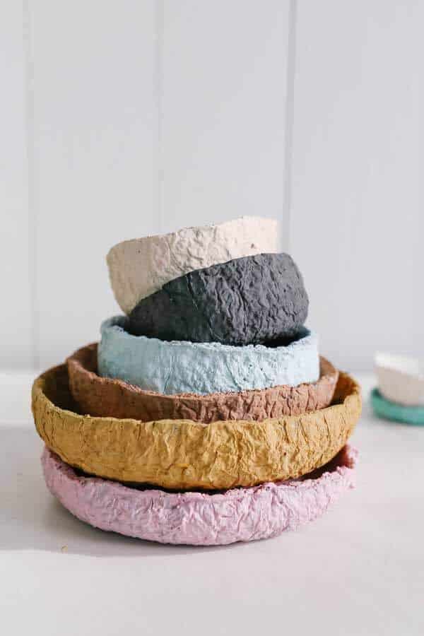 Stack of colorful handmade paper mache bowls on a white background.