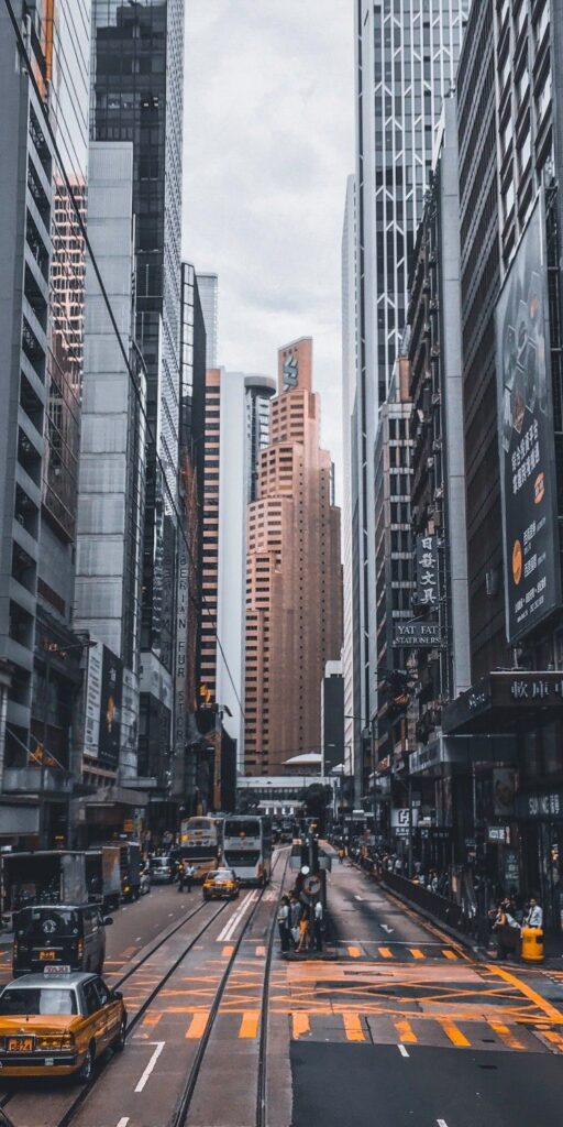 Busy urban street with tall skyscrapers and yellow taxis under cloudy sky.