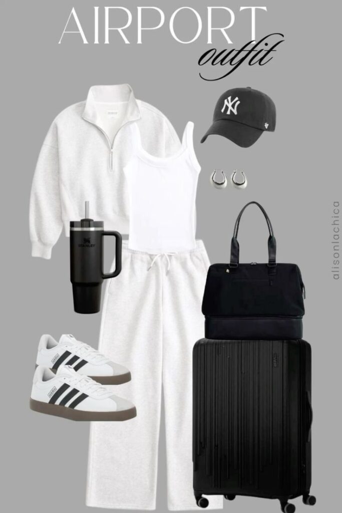 Stylish airport outfit with a white tracksuit, cap, sneakers, tote bag, suitcase, and travel mug on a grey background.