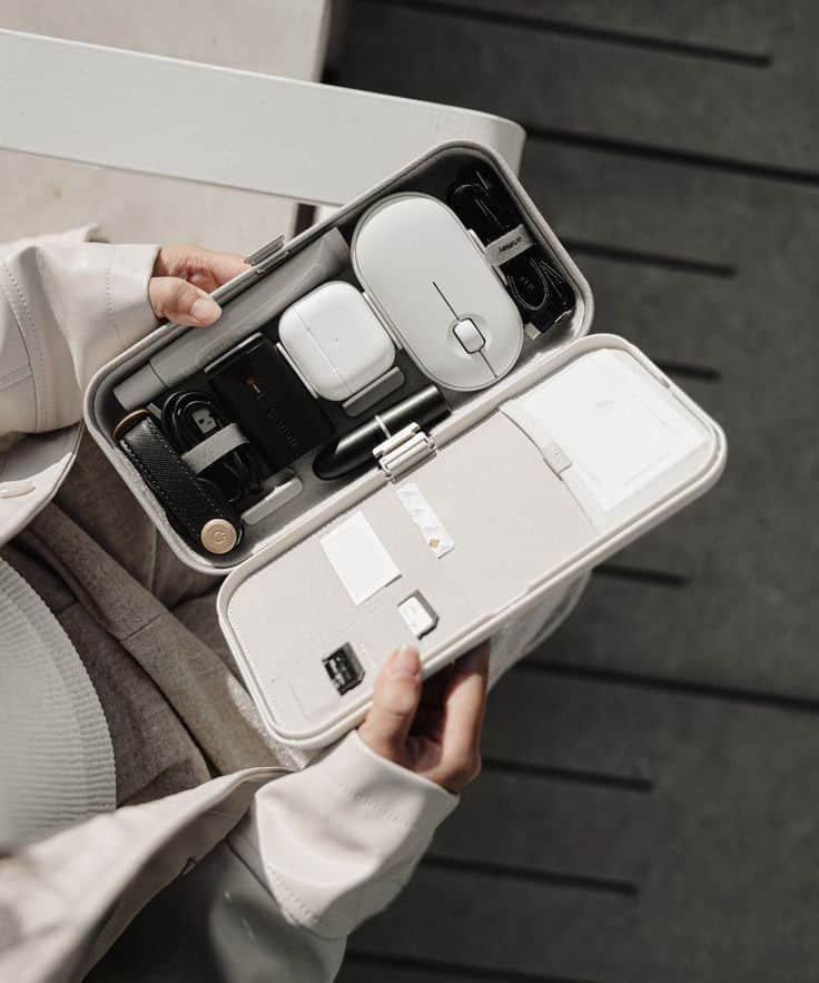 Travel tech organizer with gadgets and accessories, open in hands. Keep your tech essentials organized on the go.