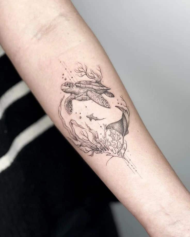 Sea turtle and marine life tattoo on forearm, featuring coral and a small shark in a detailed black ink design.