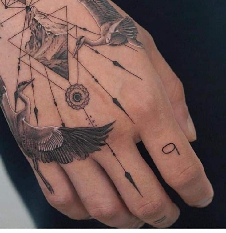 Geometric hand tattoo with cranes, mountain, and dreamcatcher design on skin.