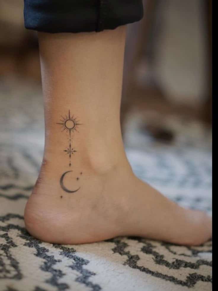 Minimalist sun and moon tattoo on ankle, featuring celestial symbols on a patterned carpet background.