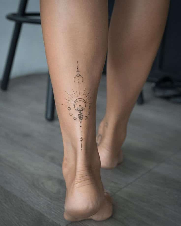 Geometric calf tattoo with crescent moon and intricate line design, on smooth skin, indoors.