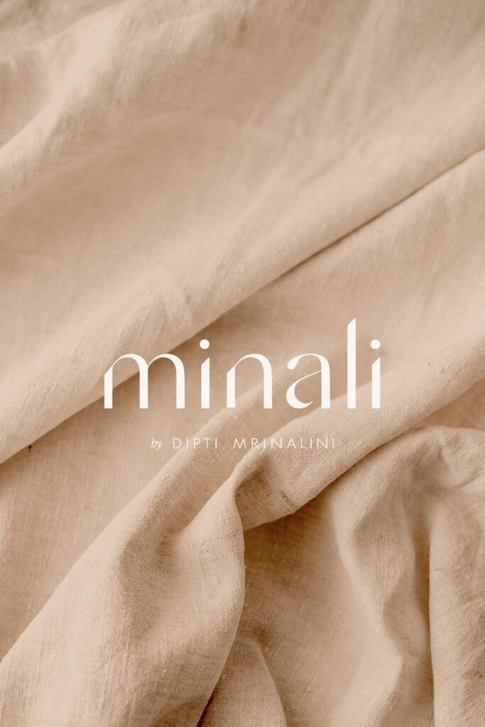 Soft beige fabric texture with minali by Dipti Mrinalini text overlay, emphasizing natural textile design.