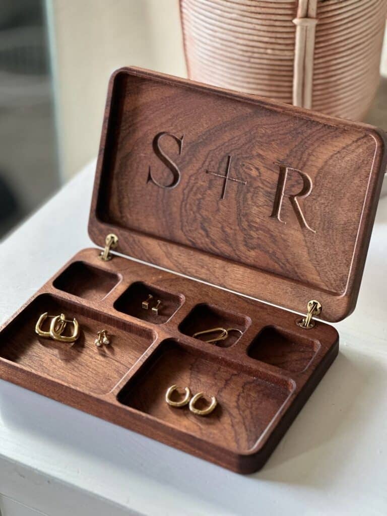 Wooden jewelry box engraved with S+R, displaying assorted gold earrings.