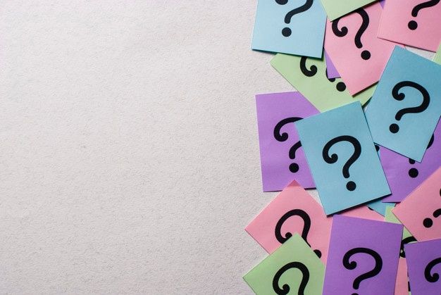 Colorful question mark notes scattered on a blank surface, symbolizing curiosity and unresolved queries.