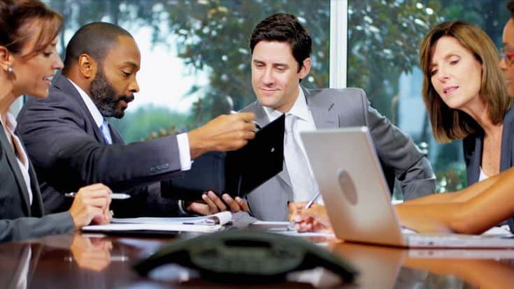 Business team collaborating at a conference table with laptops and documents, engaging in a productive meeting.