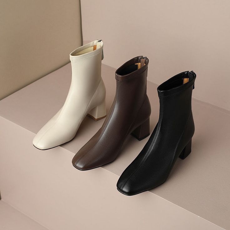 Three stylish ankle boots in cream, brown, and black displayed on a neutral background.