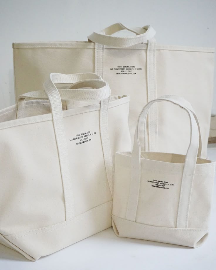 Three stylish white canvas tote bags with store brand text. Different sizes for versatile storage solutions.