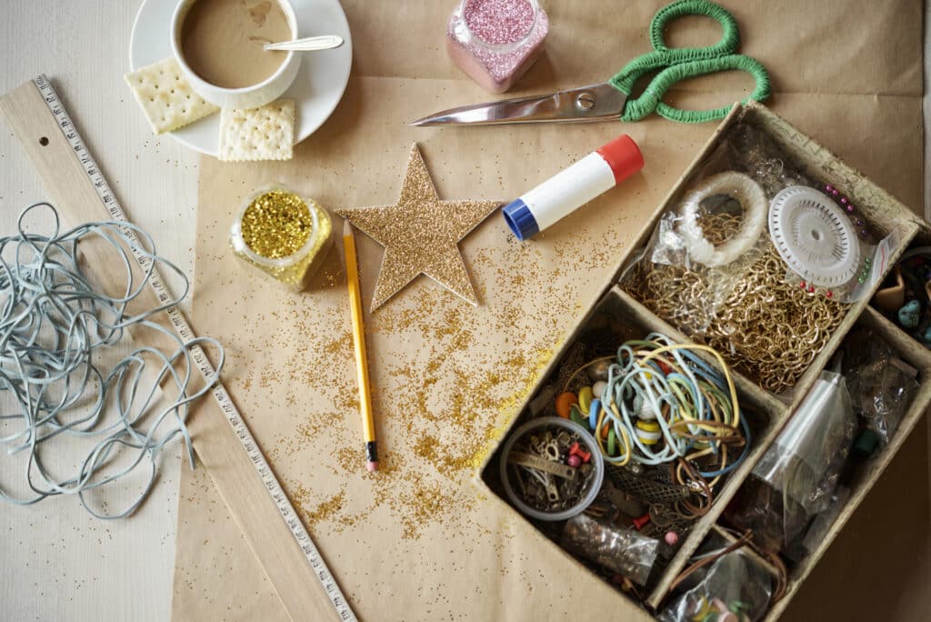 Craft supplies on a desk with glitter, star cutout, scissors, glue, and coffee. Ideal for creative DIY projects.