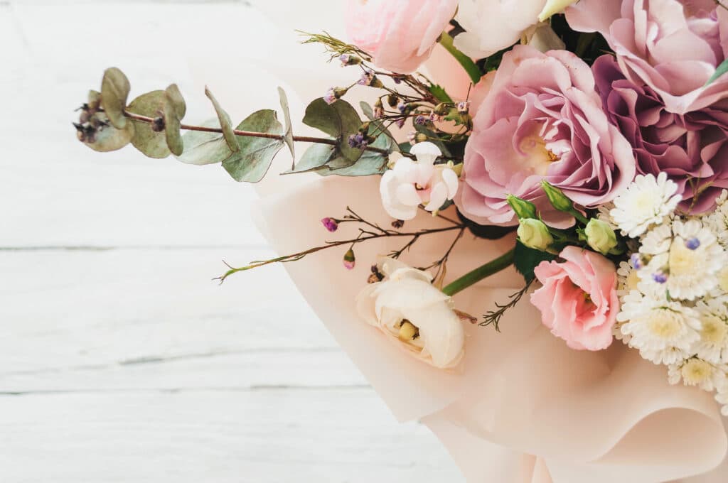 Bouquet of pastel roses and flowers on white wooden background, elegant floral arrangement, delicate and romantic.