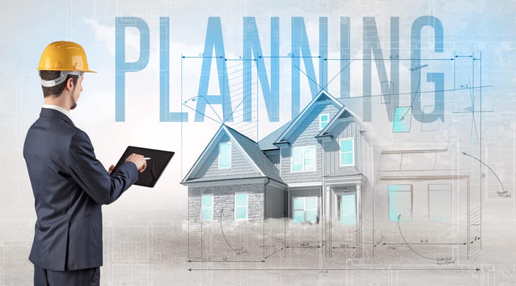 Architect planning house design with digital tablet and blueprints in the background.