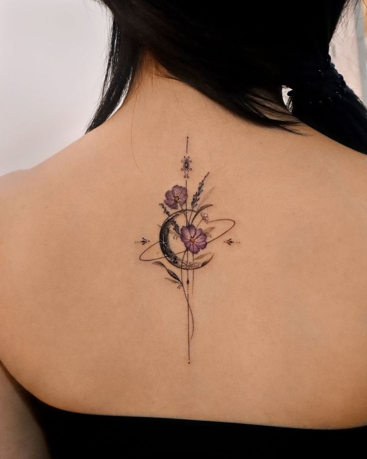 Back tattoo featuring a crescent moon and purple flowers, combining celestial and floral elements.