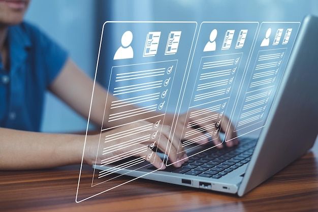 User typing on laptop with digital profiles displayed on the screen, representing online data management or digital resumes.
