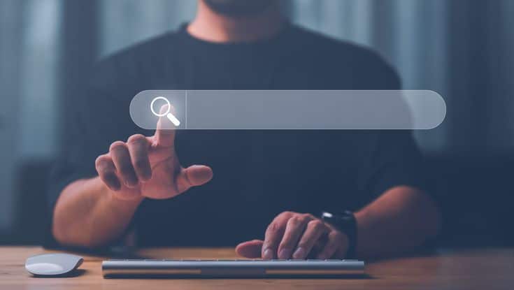 Man interacting with a virtual search bar on a screen, symbolizing online search and digital information access.