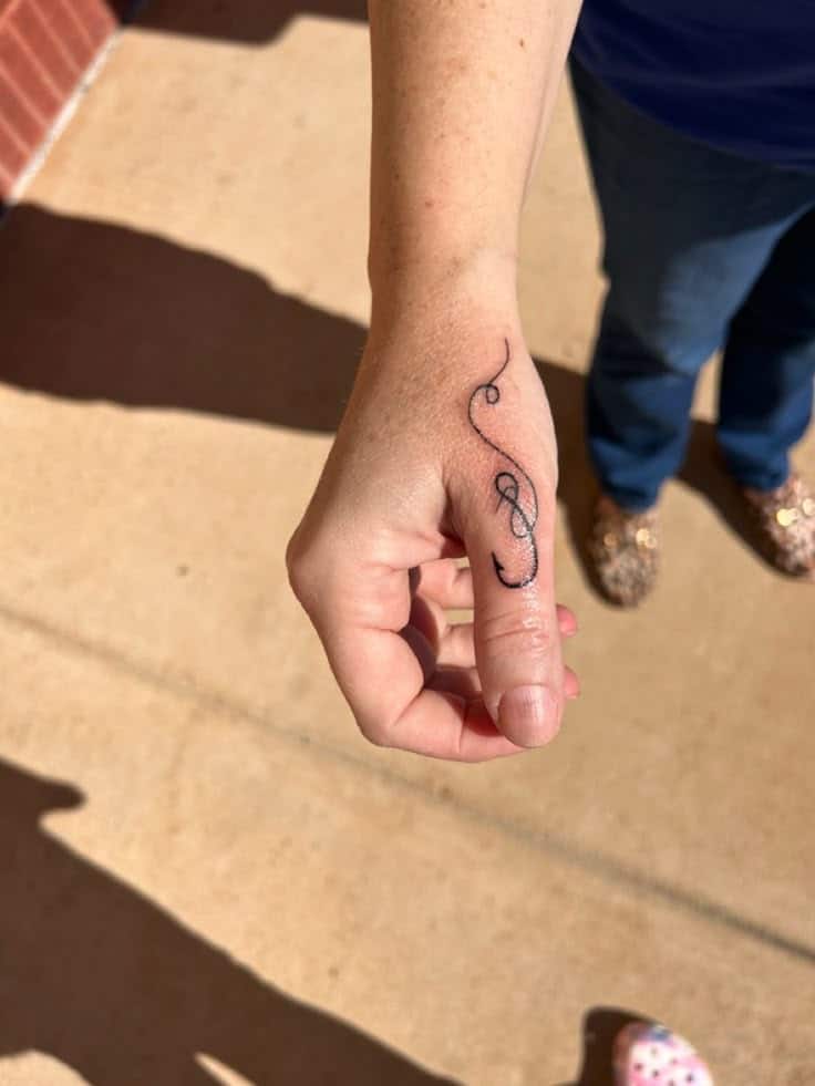 In memory of William ❤️ Close-up of a hand with a small treble clef tattoo on the finger, displayed outdoors in natural light. | Sky Rye Design Close-up of a hand with a small treble clef tattoo on the finger, displayed outdoors in natural light.