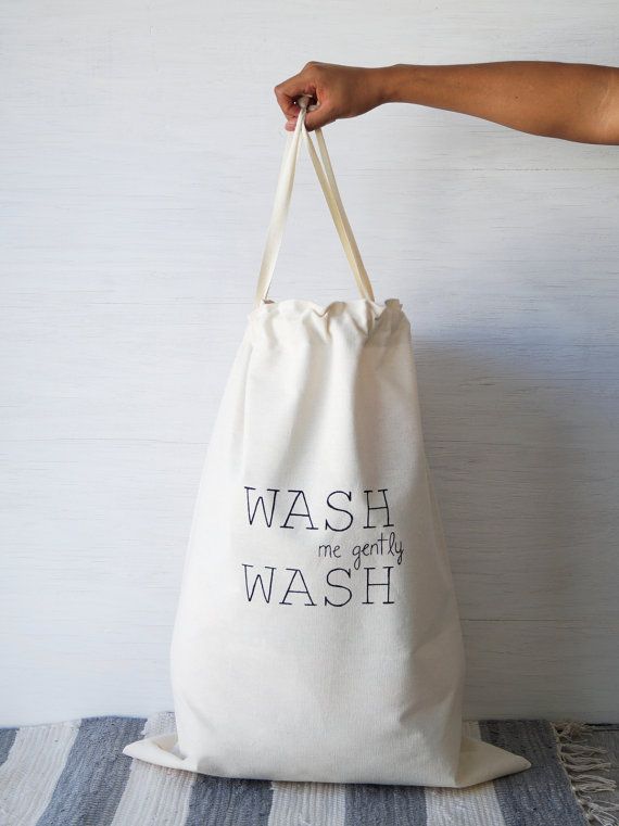 Canvas laundry bag with Wash me gently text, held by hand on a white background.