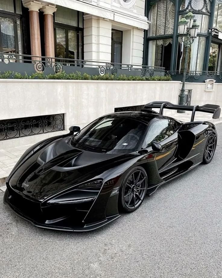 Sleek black sports car parked in an urban setting, showcasing modern architecture and luxury design.