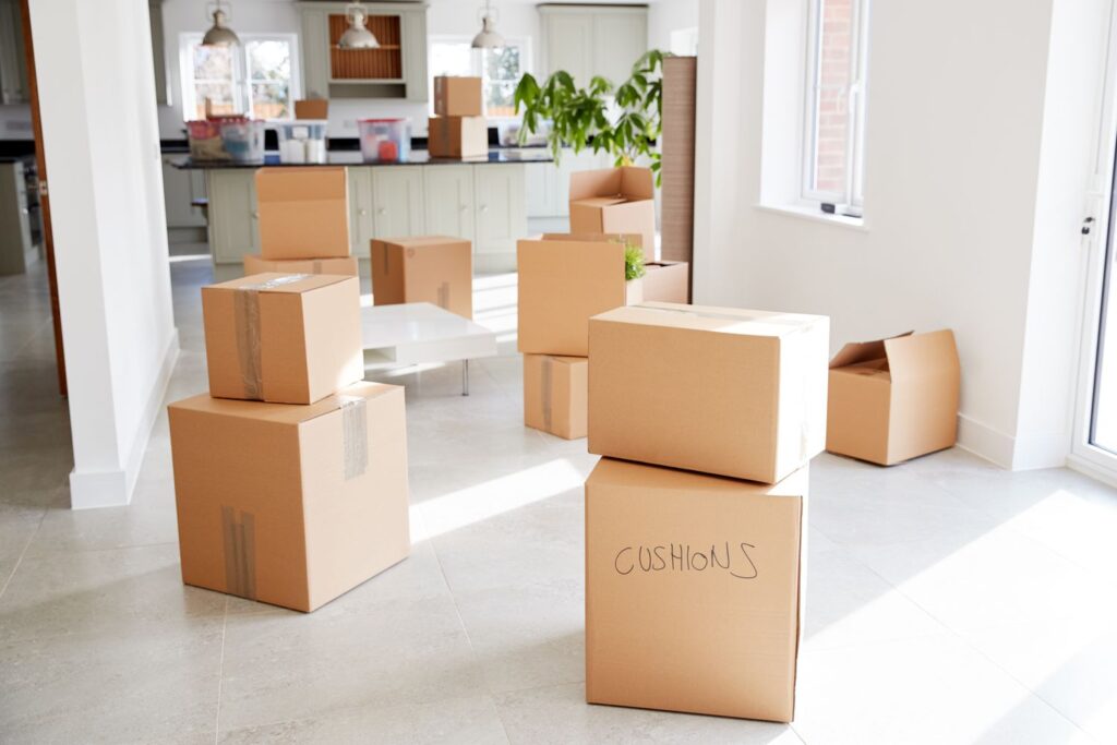 Cardboard moving boxes in a bright, open kitchen space, ready for a house move.