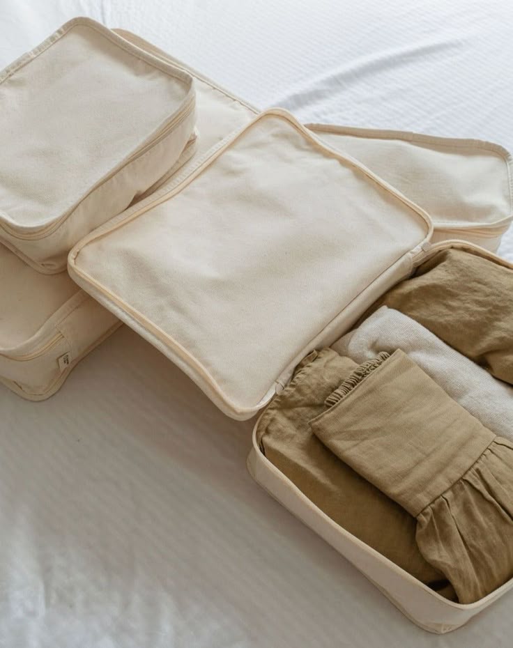 Beige travel packing cubes with clothes, neatly organized on a bed, for efficient packing and travel essentials.