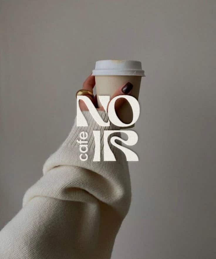 Cozy sweater hand holding coffee cup at Cafe Noir, minimalistic design.