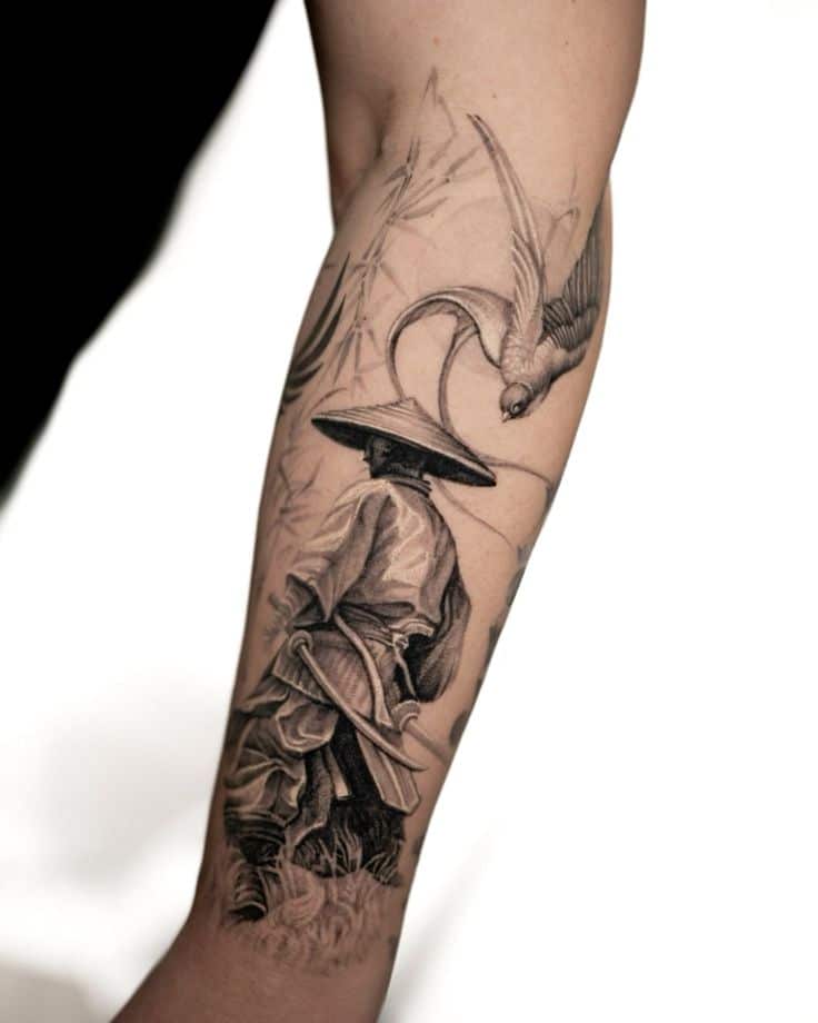 Tattoo depicting a samurai and a bird on a person's forearm, artfully detailed in black ink.