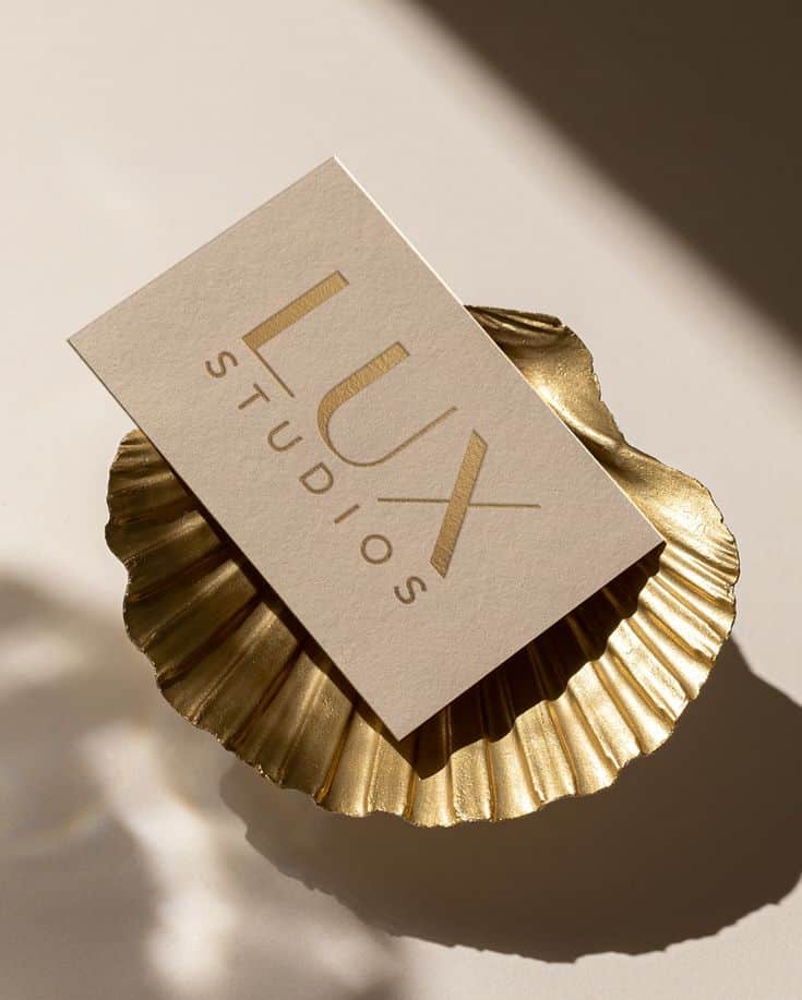 Lux Studios card on a golden shell-shaped dish, illuminated by soft shadows.