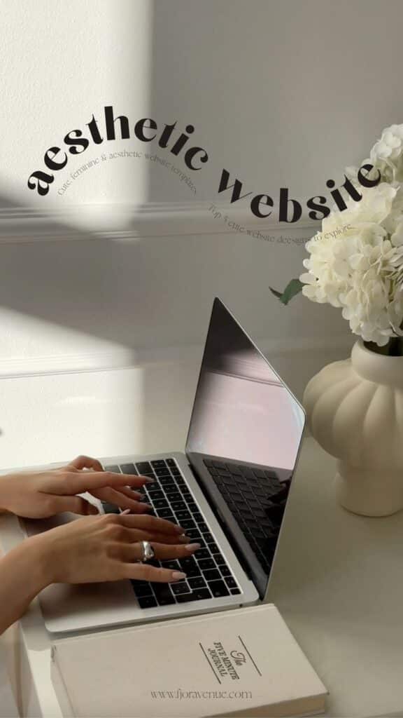 Person typing on a laptop in a bright, minimalist space with flowers and a journal nearby.