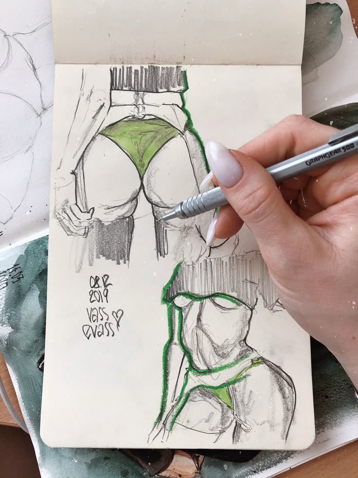 Hand sketching fashion illustrations in a notebook with a mechanical pencil.