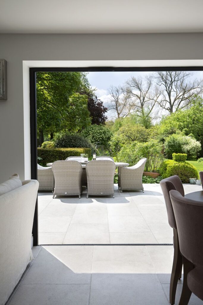 Spacious patio view with outdoor dining set overlooking lush green garden, ideal for summer relaxation and entertaining.