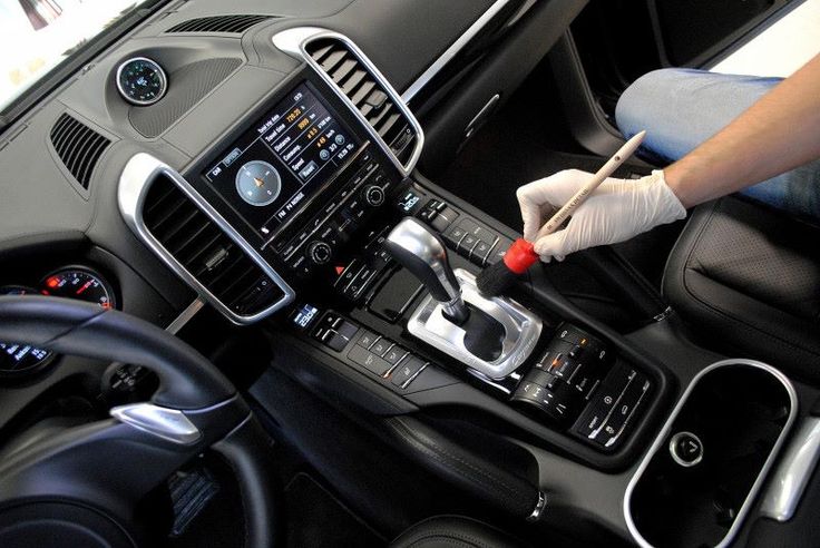 Tips detailing Cars Person cleaning luxury car interior with brush near gearshift, enhancing dashboard details and maintaining hygiene. | Sky Rye Design Person cleaning luxury car interior with brush near gearshift, enhancing dashboard details and maintaining hygiene.