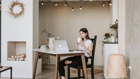 Viewing Deck Blog - 2025-07-24T203334305 Modern home office with woman at a desk, using a laptop and sipping coffee, surrounded by cozy decor and soft lighting. | Sky Rye Design Modern home office with woman at a desk, using a laptop and sipping coffee, surrounded by cozy decor and soft lighting.