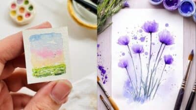 Miniature watercolor landscape and purple floral painting with brushes and paint palette.
